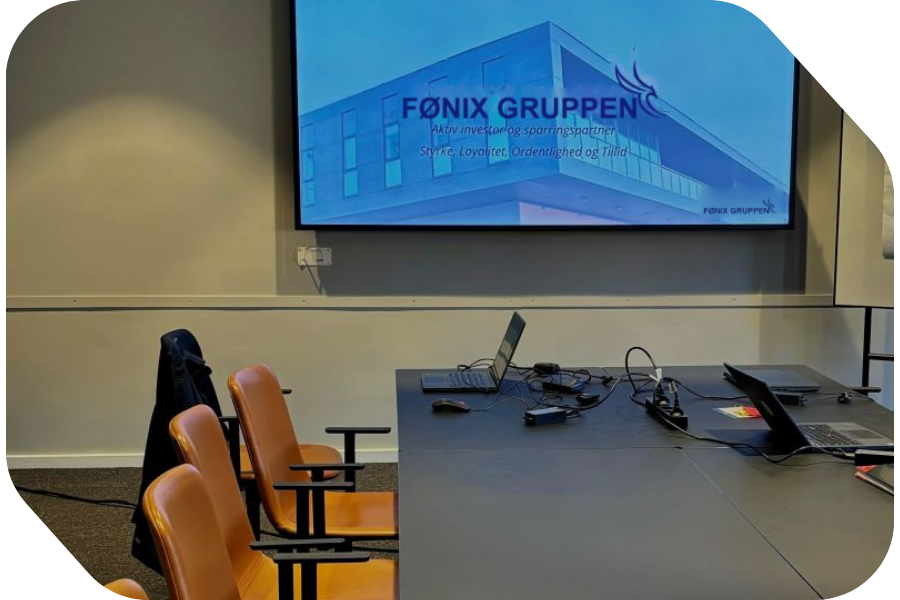 Mødelokale hos Fønix Gruppen med logoet på skærmen
